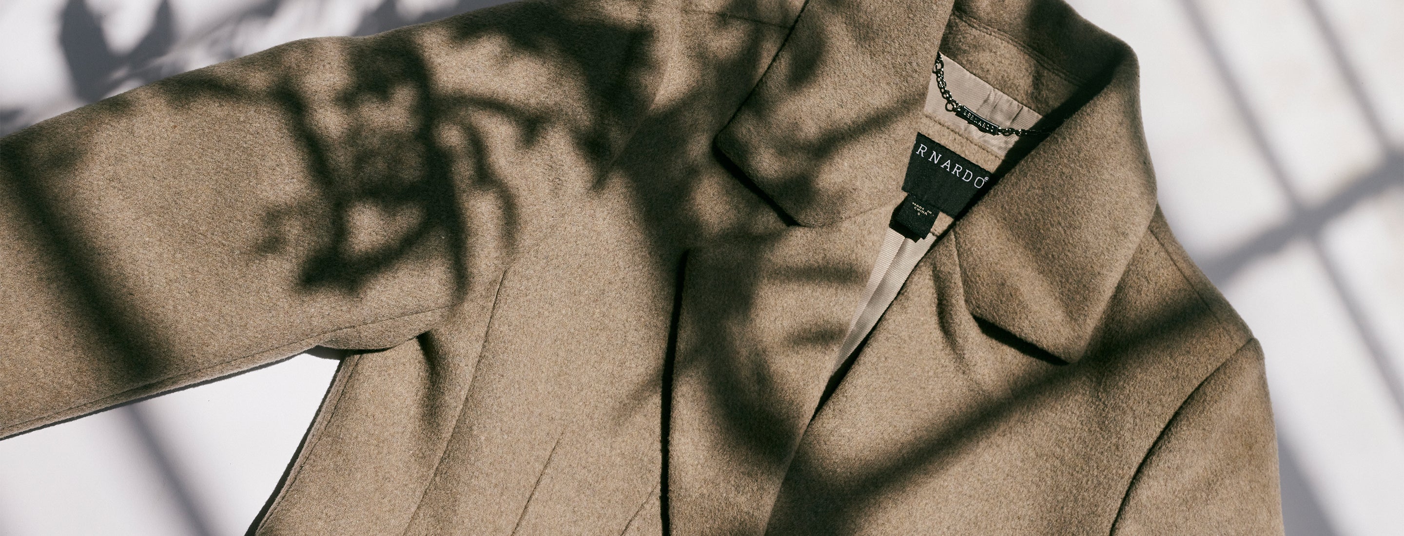 Brown Bernardo wool coat lying flat on a white background 