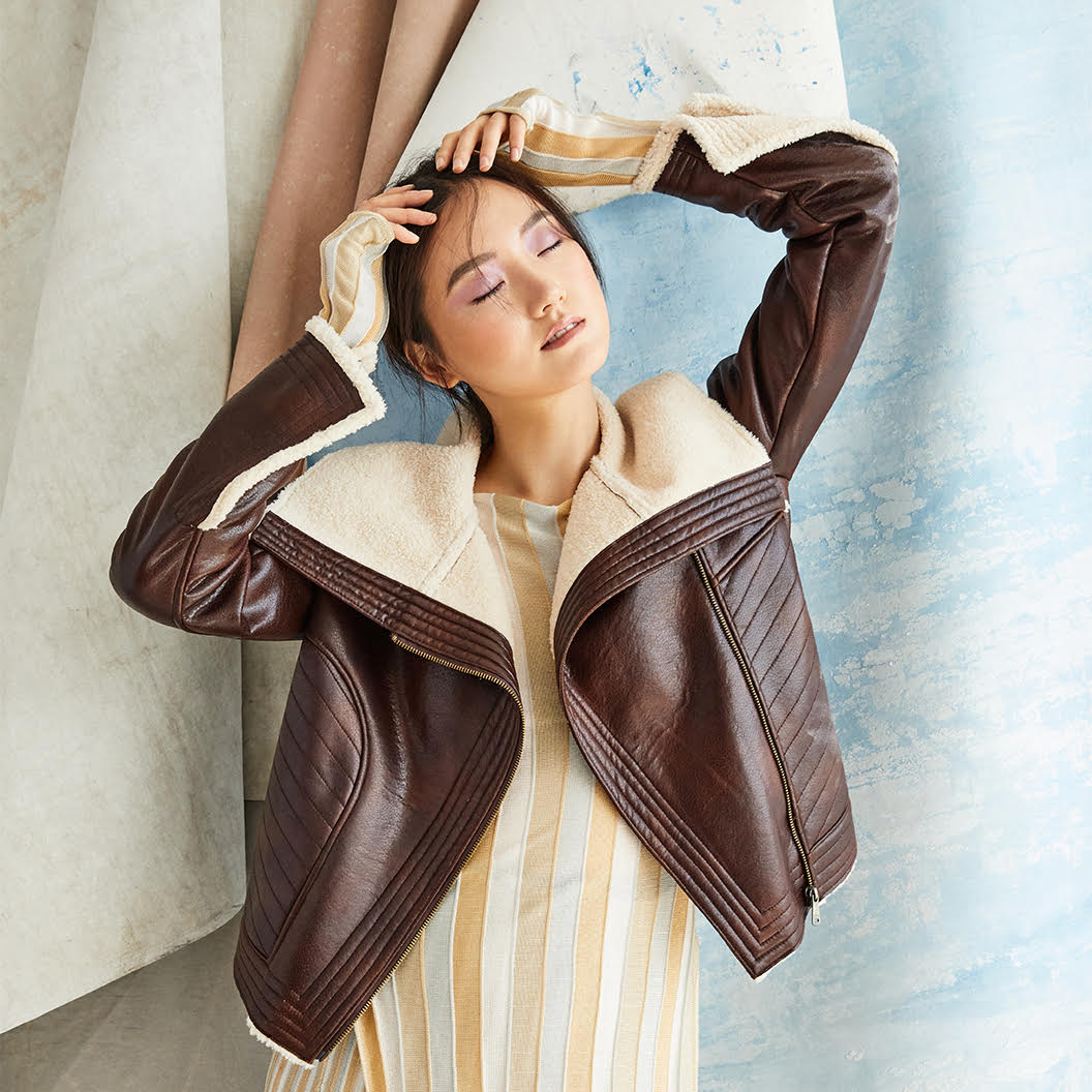 Model in a brown leather Bernardo jacket and yellow-and-white striped dress 